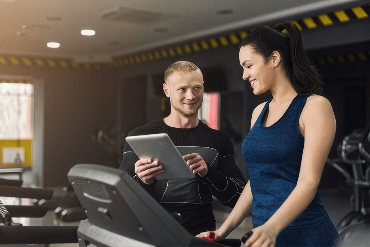 Seorang pelatih membantu member saat sesi latihan di gym